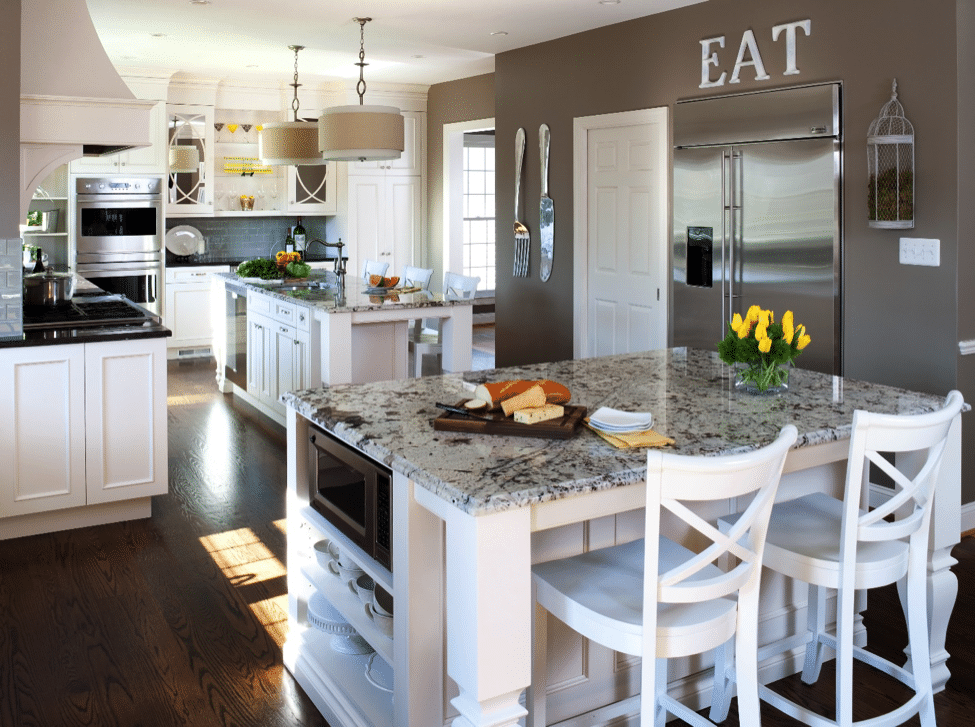 Large remodeled kitchen with white traditional style cabinets, gray-and-white granite countertops, two islands with stool seating, dark wood floors.