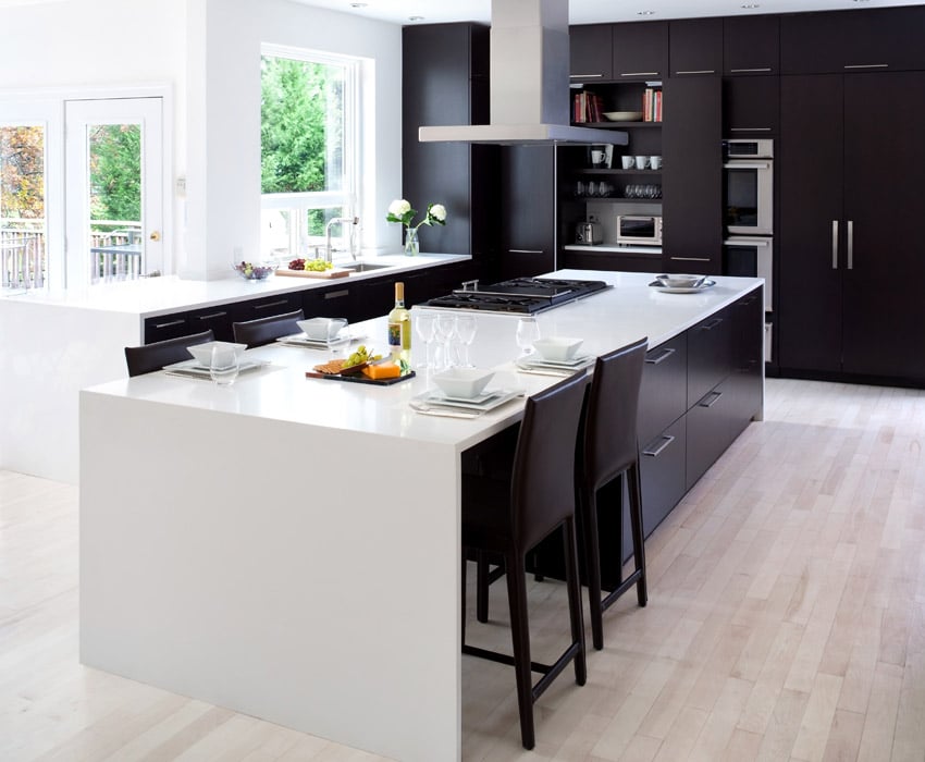 Remodeled kitchen with black cabinets and long white-stone island.