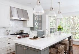 A gray and white kitchen with wicker stools at the breakfast bar.