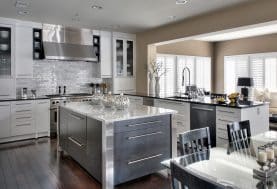 A modern, industrialist kitchen with white cabinets, a large center island and black and silver accents