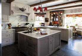 a grey and white kitchen with a marble backsplash and red accents