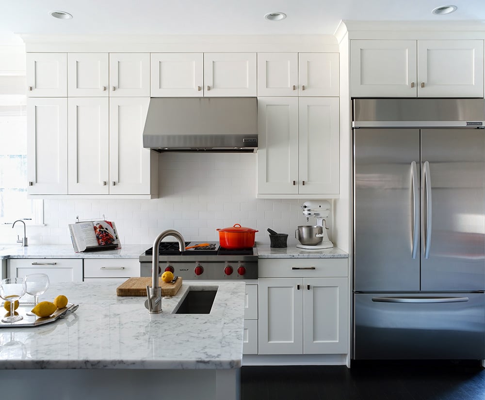 A minimalistic white kitchen with silver appliances