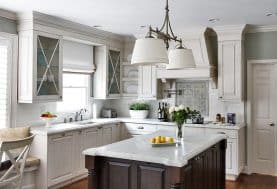 A white kitchen with a large dark wood island and marble countertop