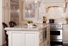A girly cream-beige kitchen with silver appliances, a crystal chandelier, and mosaic tile backsplash