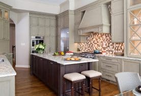 A large grey kitchen with floor to ceiling cabinetry, warm wooden floors, and a large center island